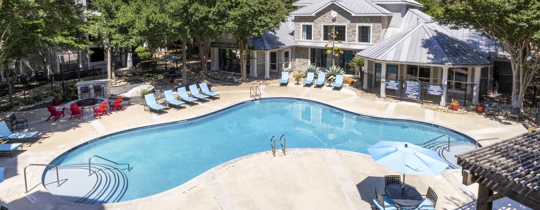a swimming pool with chairs and umbrellas next to a house