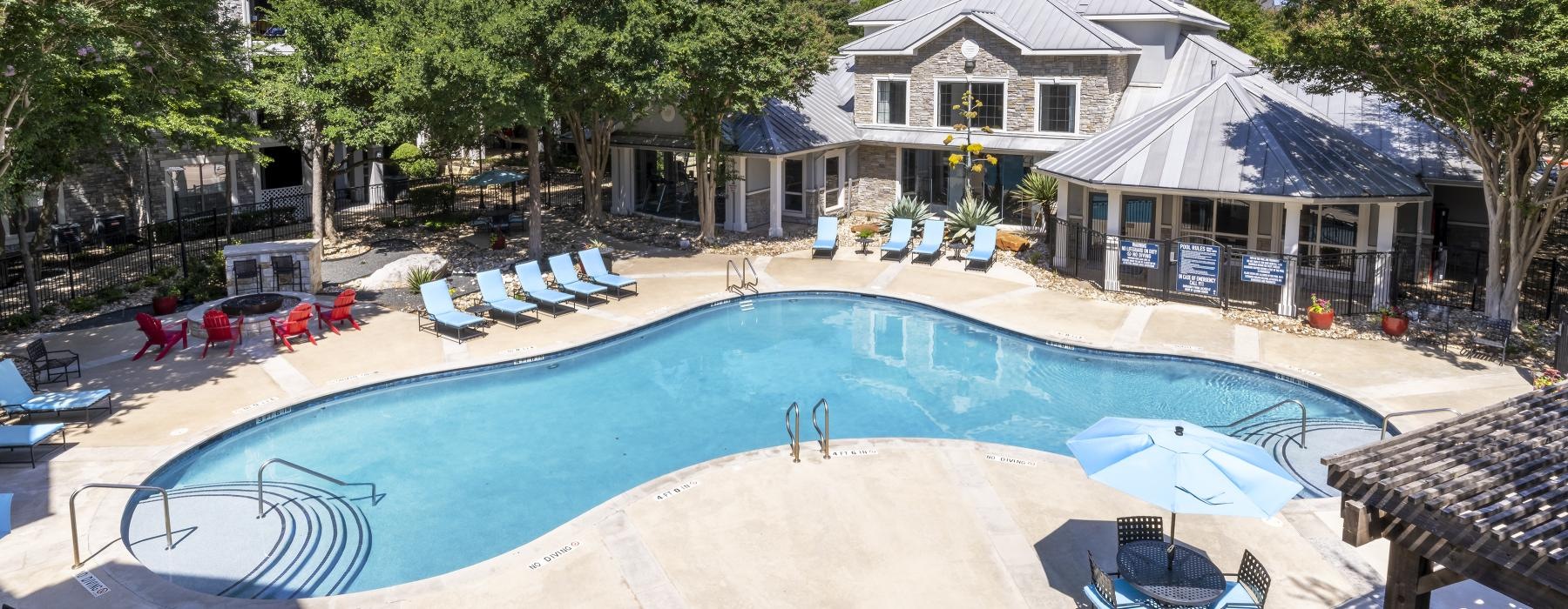 a swimming pool with chairs and umbrellas next to a house